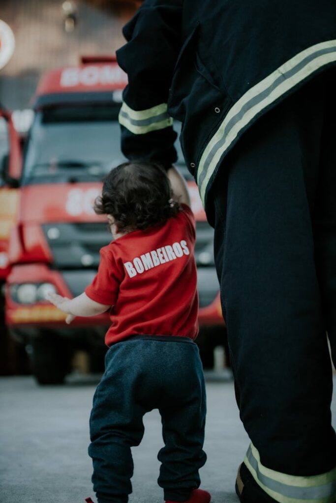 A firefighter guiding a child near a fire truck, showcasing safety and courage.